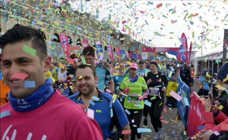 Smiling runners start a marathon with clouds of colourful confetti filling the air